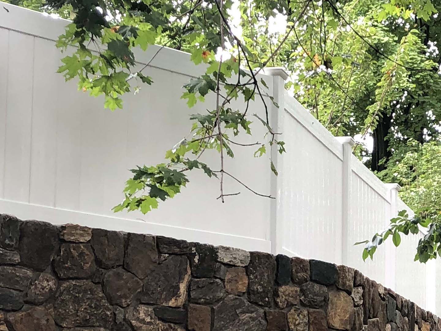 White Full-Privacy Vinyl Fence on Rock Wall for Homes in Tewksbury MA